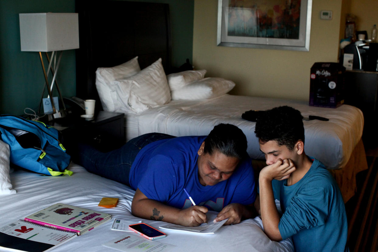 Liz Vazquez helps her son Raymond Fernandez Vazquez with his homework in an Orlando, Florida hotel room, where they've been living since being displaced by Hurricane Maria, on December 6, 2017. (Photo: Alvin Baez / Reuters)