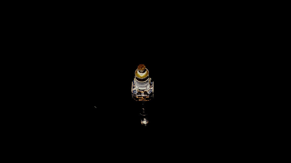     A lone spacecraft hangs in the solid black of space. 