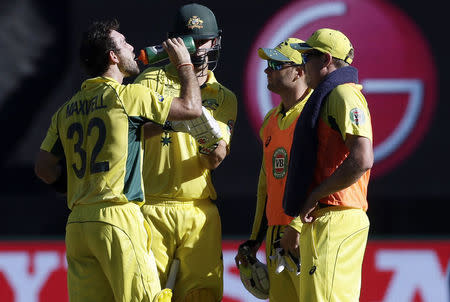 Australia's Glenn Maxwell (L) and teammate Mitchell Marsh have a drink delivered by injured team captain Michael Clarke (2nd R) and James Faulkner (R) during the Cricket World Cup match against England at the Melbourne Cricket Ground (MCG) February 14, 2015. REUTERS/Hamish Blair