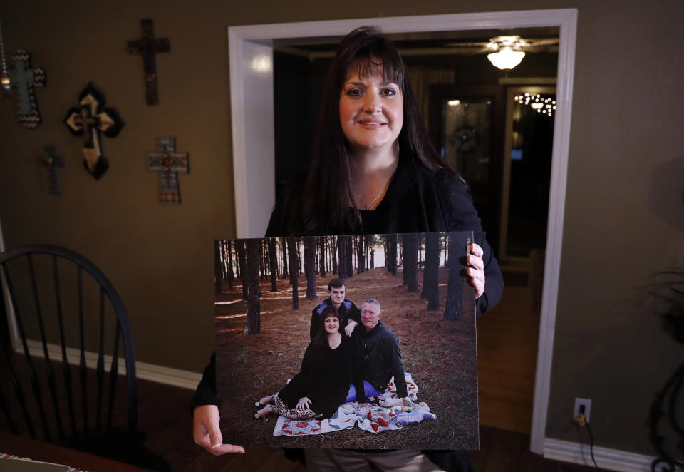In this Thursday, Dec. 20, 2018 photo, Reagen Adair poses for a photo at her home holding a portrait of herself, with her husband Dale and son Mason, in Murchison, Texas. Adair, a fifth-grade teacher, had $3,100 in debt erased by RIP Medical Debt. The co-founders of RIP buy millions of dollars in past-due medical debt for pennies on the dollar. (AP Photo/Tony Gutierrez)