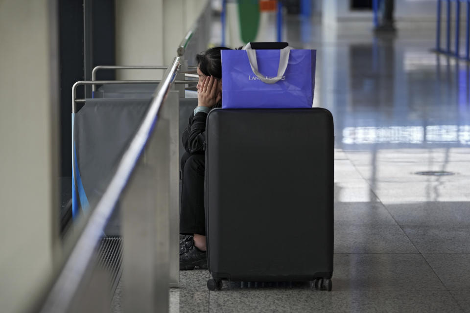 A passenger reacts as she sits near her luggage after all flights were cancelled at Pudong International Airport in Shanghai, China, Sunday, July 25, 2021. Airline flights were canceled in eastern China and cargo ships were ordered out of the area Saturday as Typhoon In-fa churned toward the mainland after dumping rain on Taiwan. (AP Photo/Andy Wong)