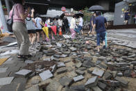 People walk on a damaged road near a subway station in Seoul, South Korea, Tuesday, Aug. 9, 2022. Some of the heaviest rain in decades swamped South Korea's capital region, turning Seoul's streets into car-clogged rivers and sending floods cascading into subway stations.(Kim Ju-sung/Yonhap via AP)