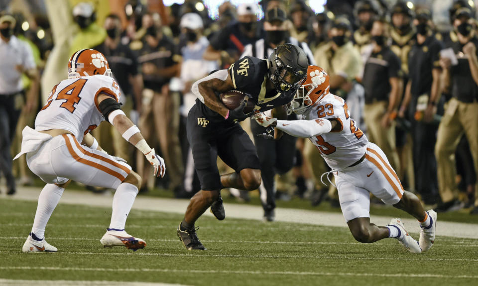 Wake Forest wide receiver Donavan Greene is stopped by Clemson defenders Nolan Turner (24) and Andrew Booth Jr. (23) in the first half of an NCAA college football game Saturday, Sept. 12, 2020, in Winston-Salem, N.C. (Walt Unks/The Winston-Salem Journal via AP)