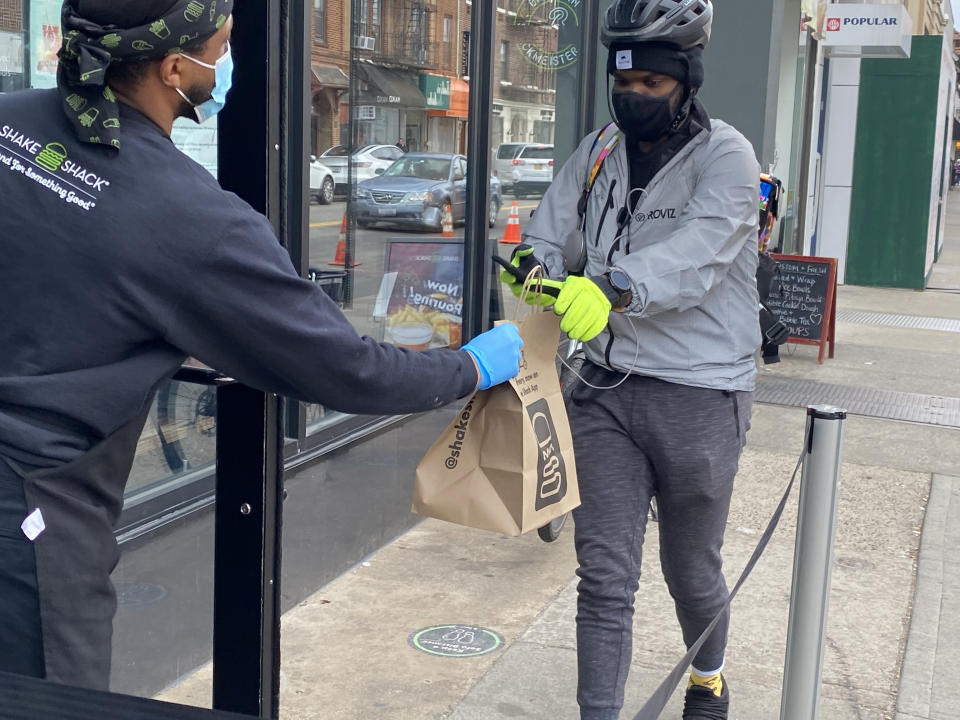 Shake Shack employee handing off food to delivery person, Queens, New York. (Photo by: Lindsey Nicholson/Education Images/Universal Images Group via Getty Images)