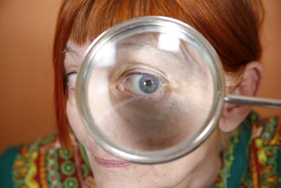 A senior woman looking through a magnifying glass.
