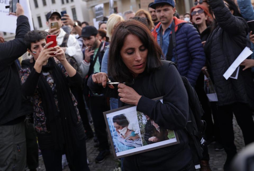 A female protester in Berlin cuts her hair with scissors as an act of solidarity with women in Iran (Getty Images)