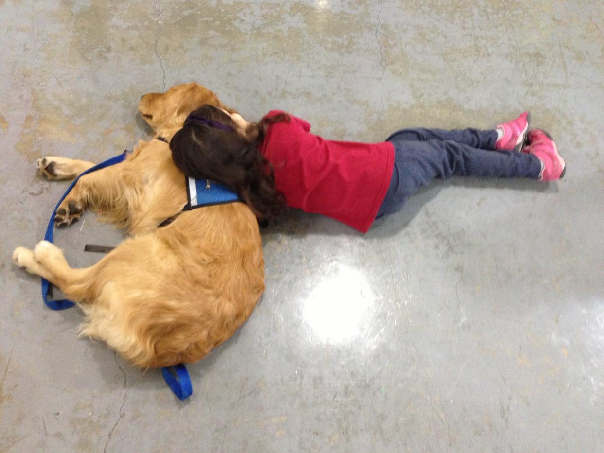 A child rests her head on one of LCC’s comfort dogs.