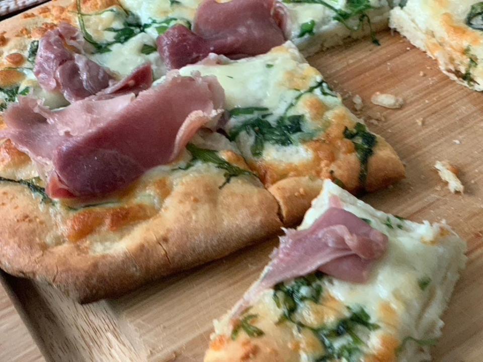 cooked Trader Joe's burrata and prosciutto flatbread on cutting board