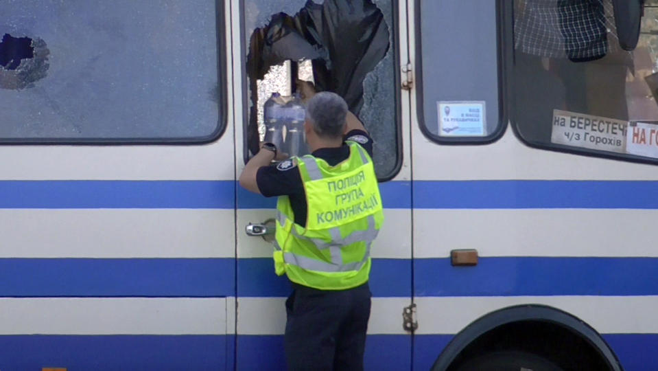 A policeman brings water for hostages contained in a bus after an armed man seized the long-distance bus and took some 10 people hostage in the city centre of Lutsk, some 400 kilometers (250 miles) west of Kyiv, Ukraine on Tuesday July 21, 2020. The assailant is armed and carrying explosives, according to a Facebook statement by Ukrainian police. Police officers are trying to get in touch with the man and they have sealed off the area. (Ukrainian Police Press Office via AP)