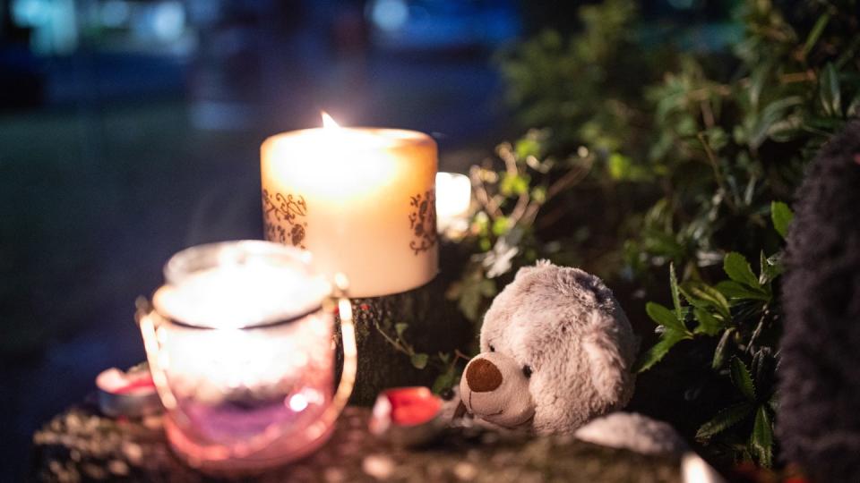 Ein Teddybär und Kerzen liegen und stehen vor einem  Haus. Eine 27-jährige Mutter soll in Solingen fünf Kinder umgebracht haben.
