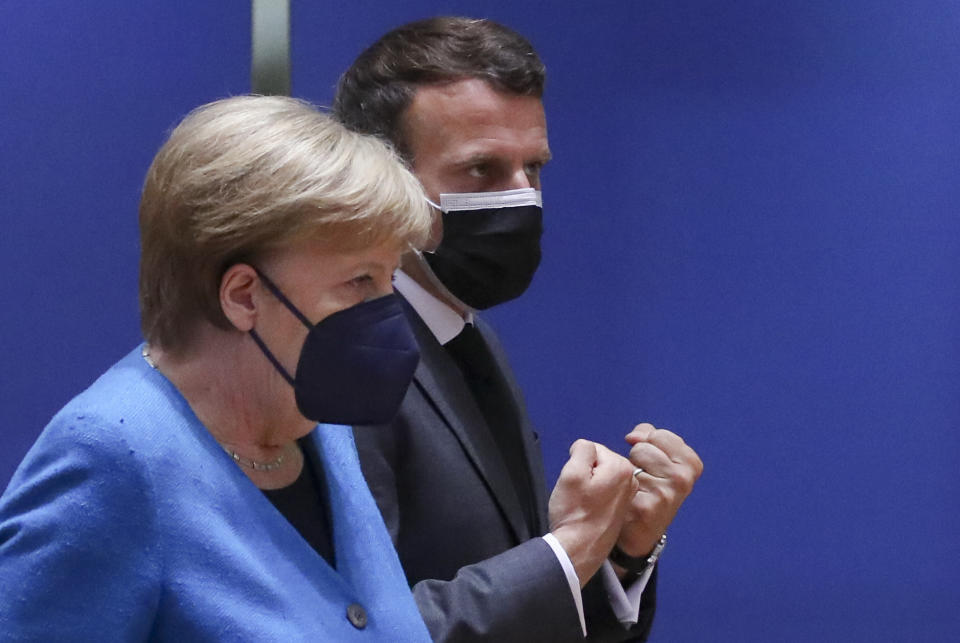 German Chancellor Angela Merkel, left, speaks with French President Emmanuel Macron during a round table meeting at an EU summit in Brussels, Monday, May 24, 2021. European Union leaders are expected, during a two day in-person meeting, to focus on foreign relations, including Russia and the UK. (Yves Herman, Pool via AP)