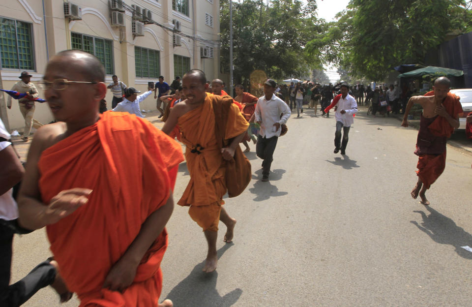 Cambodian Buddhist monks run together with supporters of Cambodian National Rescue Party from a rally site in Phnom Penh, Cambodia, Saturday, Jan. 4, 2014. Cambodian police have pushed out about 1,000 anti-government demonstrators from a park in the capital Phnom Penh, a day after four people were killed in a crackdown on a labor protest. (AP Photo/Heng Sinith)