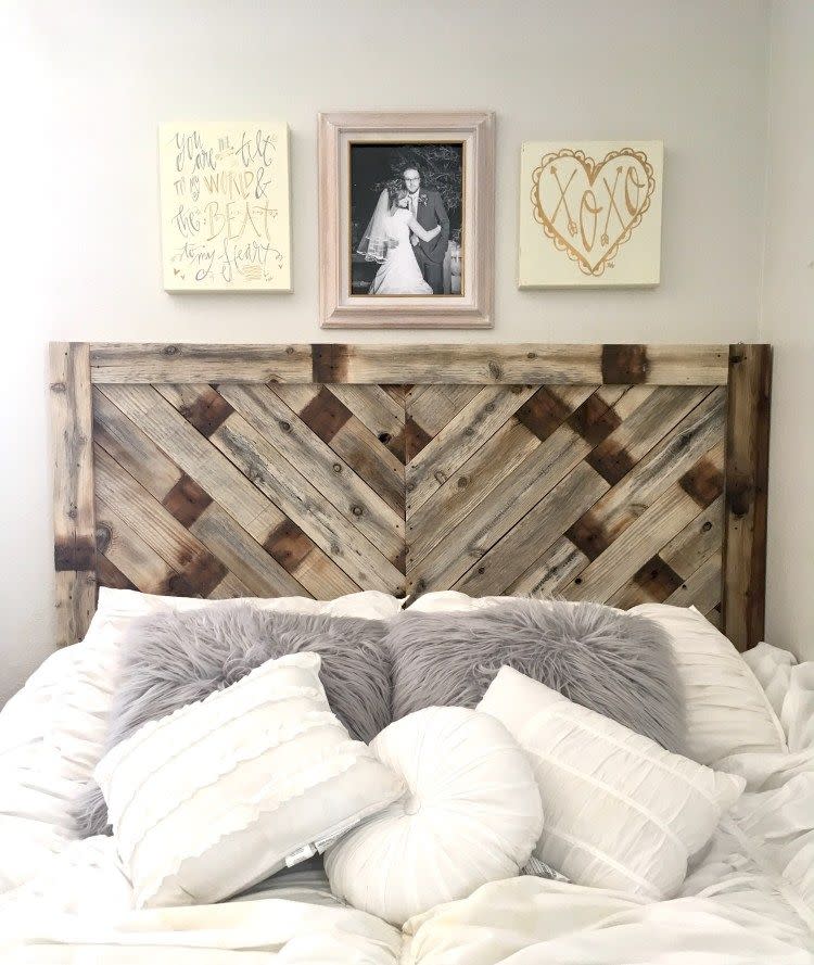 diy headboards with herringbone pallet wood frame behind white and gray pillows on a bed