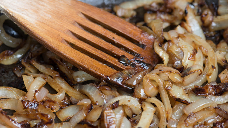 Wooden spatula stirring caramelized onions
