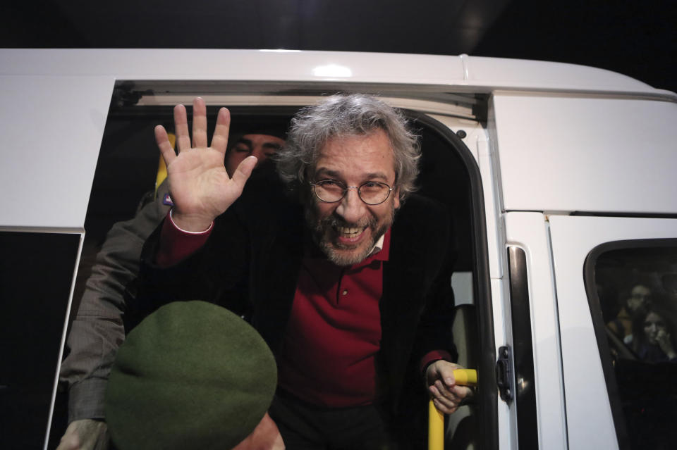 FILE- In this Friday, Feb. 26, 2016 file photo, Can Dundar, the editor-in-chief of Turkey's opposition newspaper Cumhuriyet, waves as he leaves a prison van outside the Silivri prison near Istanbul, after his release from detention. On Wednesday, Dec. 23, 2020 a court in Istanbul convicted in absentia Dundar, currently in exile in Germany since 2016, on espionage and terror-related charges for a news report. The court found Dundar guilty of "obtaining secret documents for espionage" and "aiding a terrorist organization," sentencing him to a total of 27 1/2 years in prison. (AP Photo/Can Erok, File)