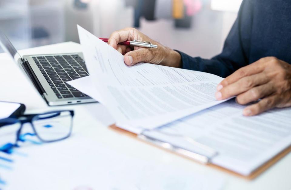 A close up of a person browsing documents in front of a laptop.