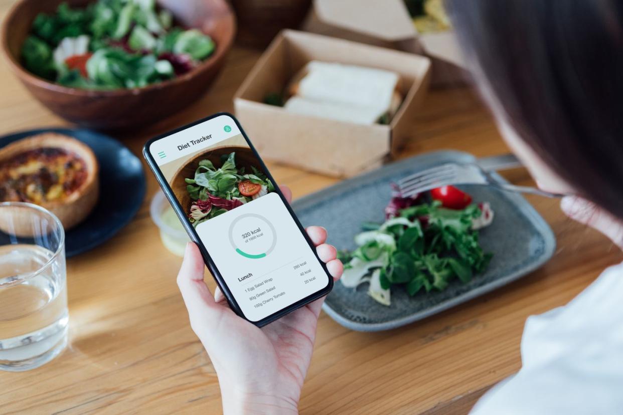 Woman using app as a food journal while eating. (Getty Images)