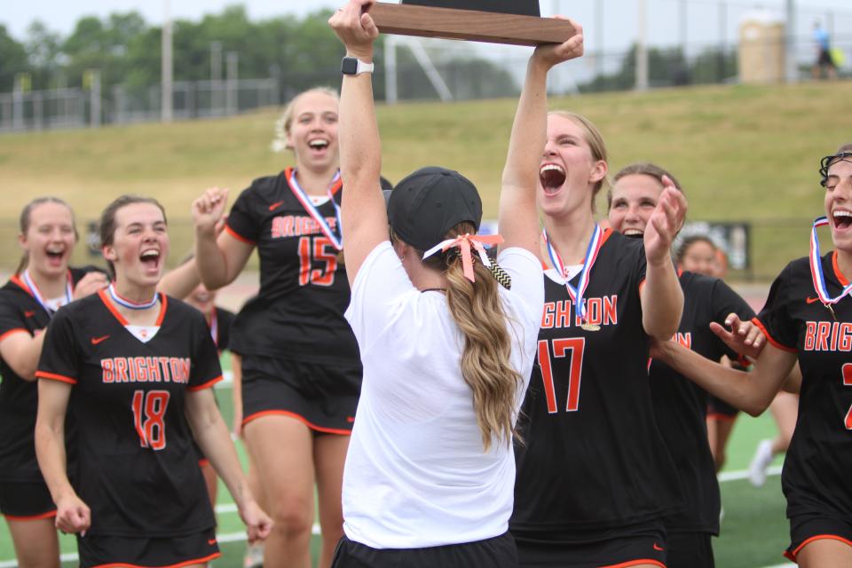 Brighton coach Ashton Peters holds up the state Division 1 lacrosse championship trophy for her players following an 8-6 victory in the Division 1 final Saturday, June 10, 2023 in Rockford.