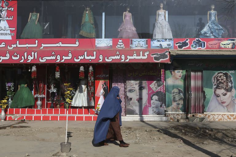 Una mujer pasa por delante de un salón de belleza y una tienda de vestidos en Kabul, Afganistán, el domingo 13 de diciembre de 2015.