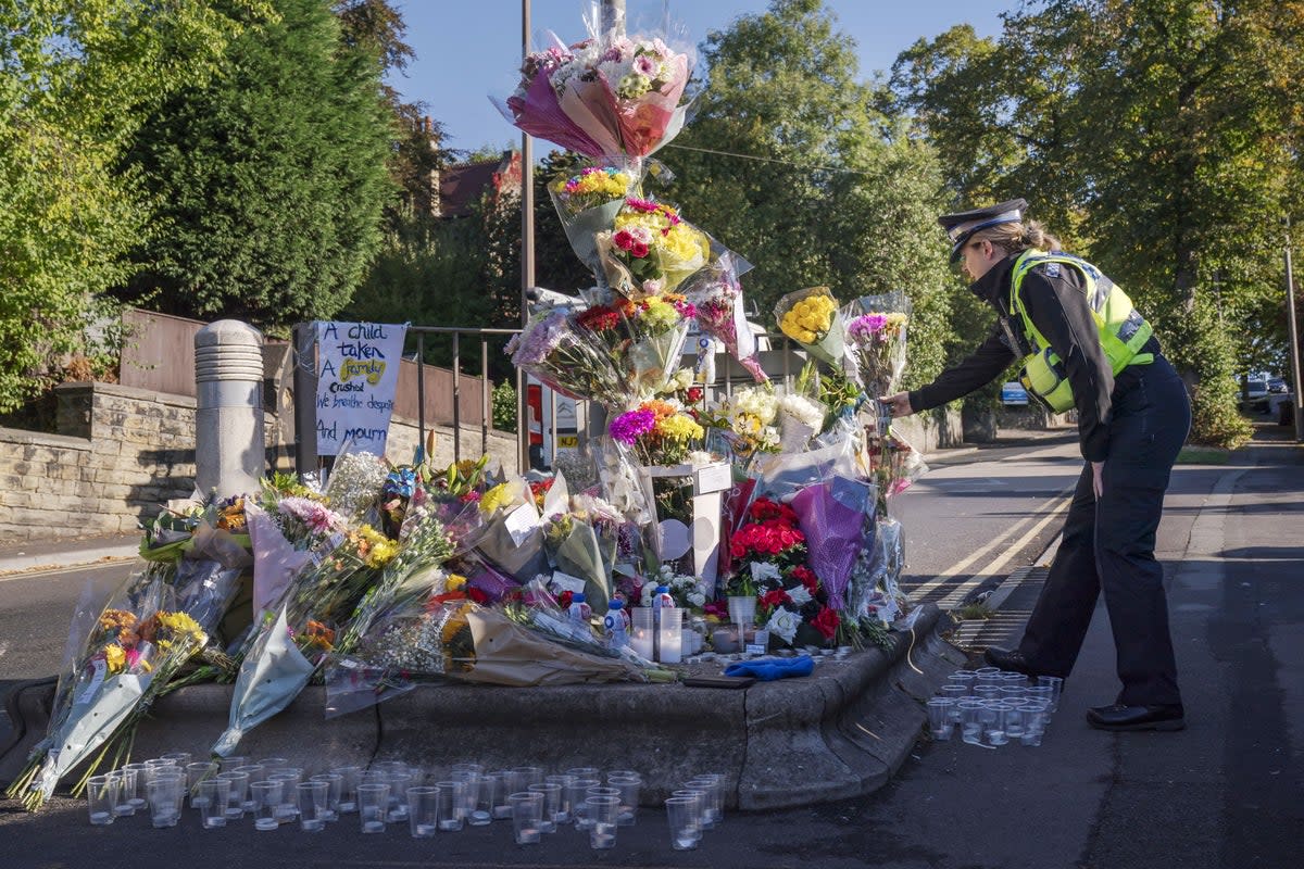 A police community support officer lays a floral tribute at the scene in Woodhouse Hill (Danny Lawson/PA) (PA Wire)