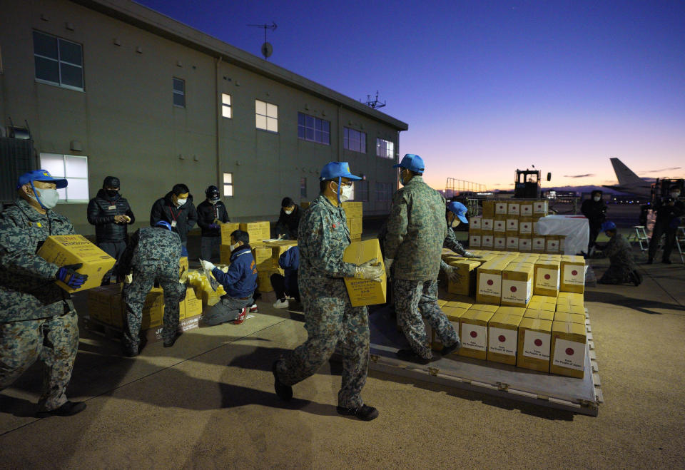 Members of Japan's Air Self-Defense Force help load boxes of water into an airplane at an airbase in Komaki, central Japan, Thursday, Jan. 20, 2022, as they were preparing to take off for Australia on their way to Tonga to transport the emergency relief goods, following Saturday's volcanic eruption near the Pacific nation. Japan's Defense Ministry said it would send emergency relief, including drinking water and equipment for cleaning away volcanic ash. (Kyodo News via AP)
