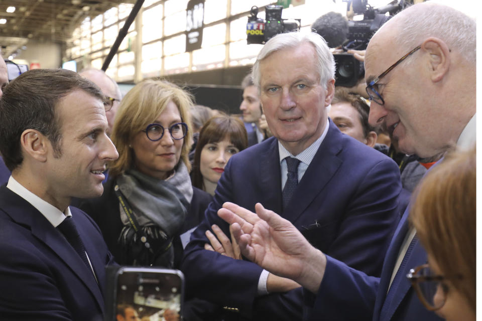 French President Emmanuel Macron discusses with European Union chief Brexit negotiator Michel Barnier, center, and European Commissioner for Agriculture Phil Hogan, right, as he visits the 56th International Agriculture Fair at the Porte de Versailles exhibition center in Paris, France, Saturday, Feb. 23, 2019. Macron pledged to protect European farming standards and culinary traditions threatened by aggressive foreign trade practices that see food as a "product like any other." (Ludovic Marin/Pool Photo via AP)