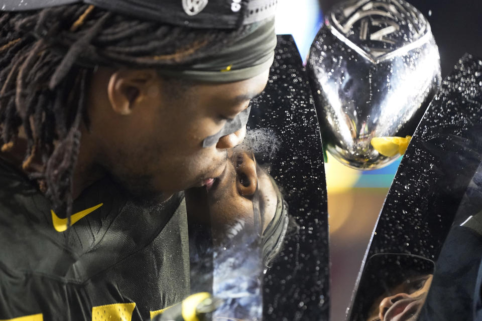 Oregon cornerback Haki Woods Jr. (14) kisses the trophy after Oregon defeated Utah 37-15 in an NCAA college football game for the Pac-12 Conference championship in Santa Clara, Calif., Friday, Dec. 6, 2018. (AP Photo/Tony Avelar)