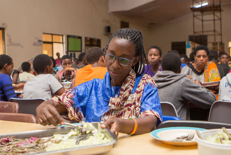 Mukarusagara Emerithe, a genocide survivor and one of the caretaker at the Agahozo-Shalom Youth Village (ASYV) built to rehabilitate children who lost their families in the 1994 Rwandan genocide, puts a meal on a plate in the dinning hall in Rwamagana, Eastern Province of Rwanda April 1, 2019. Picture taken April 1, 2019. REUTERS/Jean Bizimana