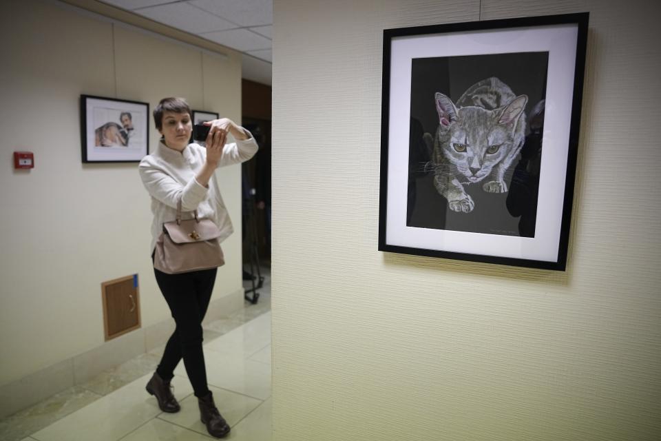 A journalist films with her smartphone during an opening of exhibition of artworks by Russian businessman Viktor Bout, who was sentenced to 25 years in the United States, at the Federation Council of the Federal Assembly of the Russian Federation in Moscow, Russia, Tuesday, Nov. 15, 2022. Russia has sought Bout's release for years and he is believed to be key to a possible prisoner exchange that could free US women's basketball star Brittney Griner. (AP Photo/Alexander Zemlianichenko)