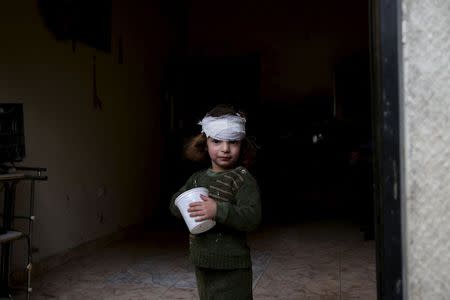 A girl, who was injured by what activists said was shelling by forces loyal to Syria's President Bashar al-Assad, stands at the entrance of her house in the Douma neighborhood of Damascus, Syria November 22, 2015. Picture taken November 22, 2015. REUTERS/Bassam Khabieh/Files