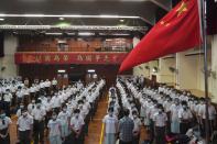 Students attend a flag raising ceremony during the National Security Education Day at a secondary school, in Hong Kong, Thursday, April 15, 2021. Beijing's top official in Hong Kong on Thursday warned foreign forces not to interfere with the "bottom line" of national security in Hong Kong, threatening retaliation even amid ongoing tensions between China and Western powers. (AP Photo/Kin Cheung)