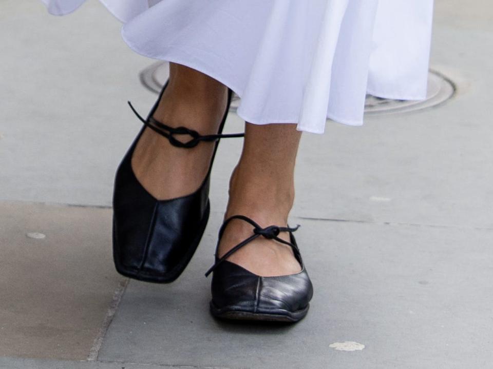 Model wearing white robe and black ballet flats.