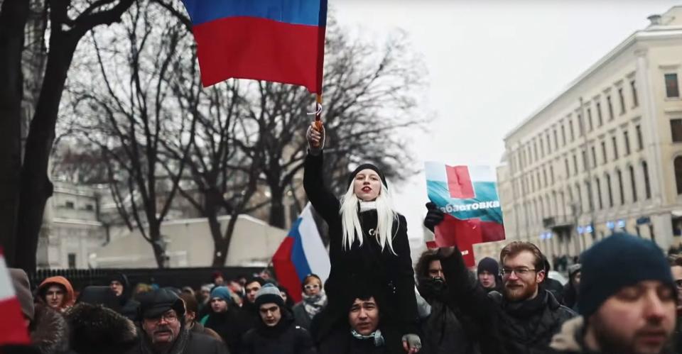 A woman holds a flag over her head in a crowd