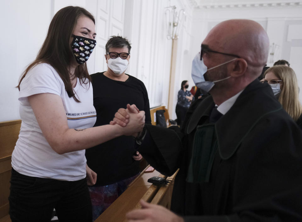 Polish activist Anna Prus, left, shakes hands with her lawyer as another activist, Elzbieta Podlesna, center, looks on in Plock, Poland, Tuesday March 2, 2021. The court acquitted three female activists who had been accused of desecration and offending religious feelings for adding the LGBT rainbow to images of a revered Roman Catholic icon. In posters that they put up in protest in their city of Plock, the activists used the rainbow in place of halos on a revered image of the Virgin Mary and baby Jesus. (AP Photo/Czarek Sokolowski)