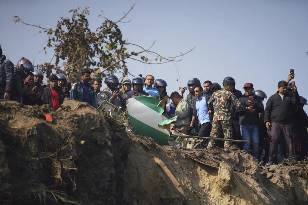 Locals watch the wreckage of a passenger plane in Pokhara, Nepal, Sunday, Jan.15, 2023. A passenger plane with 72 people on board has crashed near Pokhara International Airport in Nepal, the daily newspaper Kathmandu Post reports. The plane was carrying 68 passengers and four crew members. (AP Photo/Yunish Gurung)