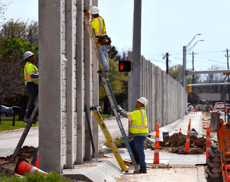 Construction men work on a portion of a new wall separating homes on Flintlock Drive from the busier Buffalo Gap Road Wednesday. The soundproofing wall is part of the renovation of Buffalo Gap Road which has been ongoing for more than a year.