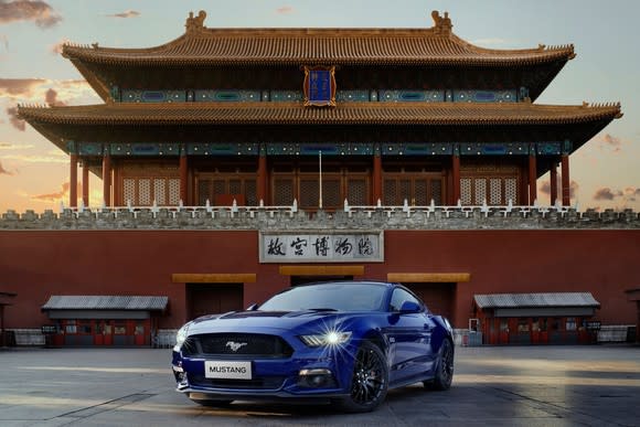 A blue Ford Mustang parked in front of a Chinese building.