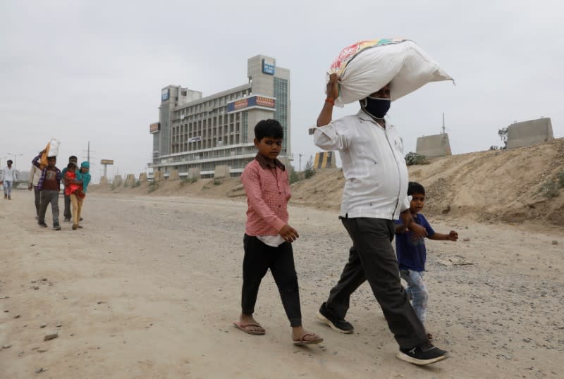 Migrant workers and their families walk on a highway as they look out for a transport to return to their villages, after India ordered a 21-day nationwide lockdown to limit the spreading of coronavirus disease (COVID-19), in Ghaziabad