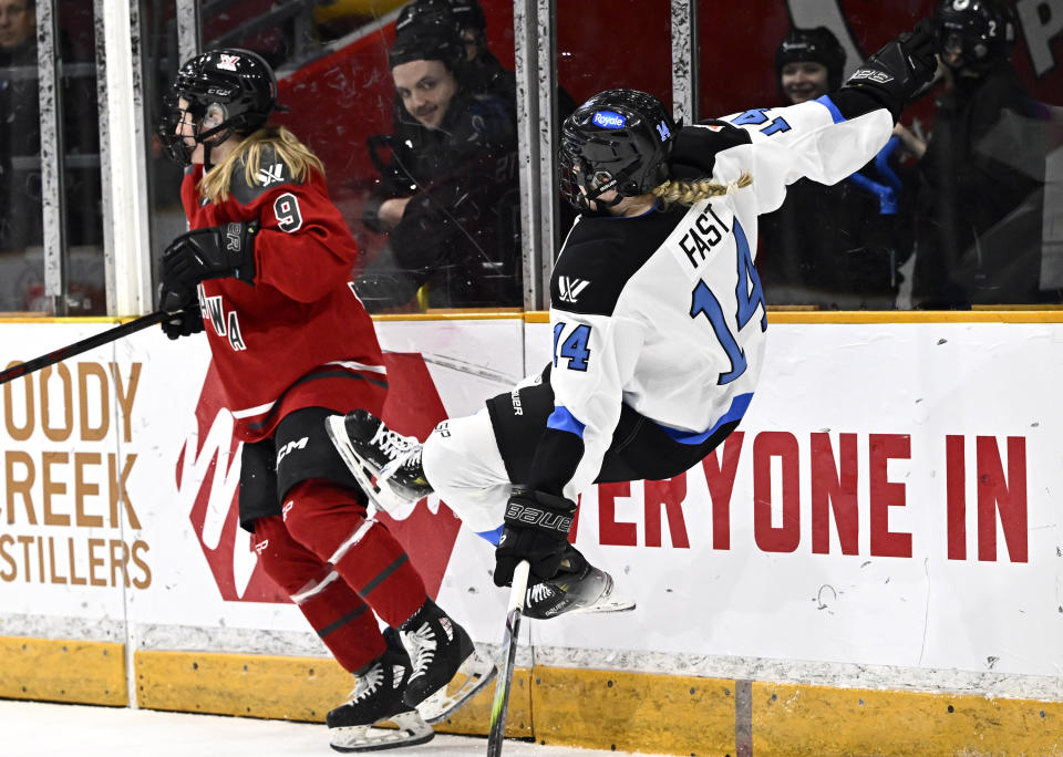 Toronto's Renata Fast (14) is knocked off her skates after crashing into the boards with Ottawa's Daryl Watts (9) during second-period PWHL hockey game action in Ottawa, Ontario, Saturday, March 2, 2024. (Justin Tang/The Canadian Press via AP)