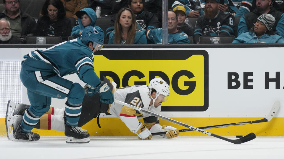 Vegas Golden Knights center Chandler Stephenson, right, reaches for the puck in front of San Jose Sharks defenseman Henry Thrun during the second period of an NHL hockey game in San Jose, Calif., Thursday, Oct. 12, 2023. (AP Photo/Jeff Chiu)