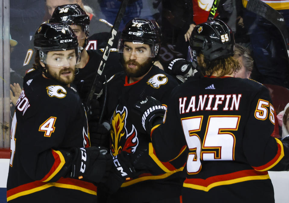 Calgary Flames forward Dillon Dube, center, celebrates his goal with teammates Rasmus Andersson, left, and Noah Hanifin during the third period of an NHL hockey game against the Tampa Bay Lightning in Calgary, Alberta, Saturday, Jan. 21, 2023. (Jeff McIntosh/The Canadian Press via AP)