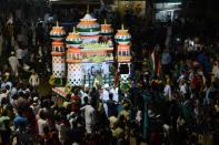 <p>Indian Muslims throng around a colourful Tazia during a procession to mark Ashura, in Ahmedabad. Devout Shiite Muslims the world over, observe Ashura rituals by beating their chests, self-flagellation, forming large processions through the streets holding banners and carrying models of the mausoleum of Hazrat Imam Hussain. </p>