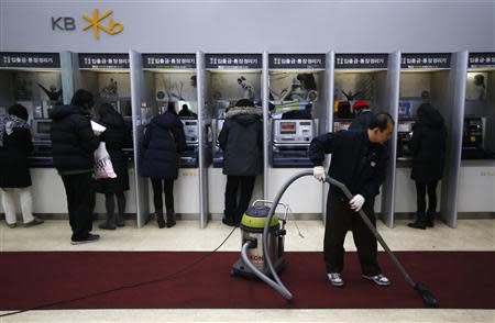 Customers use automated teller machines as a worker vacuums the floor at a branch of KB Kookmin Financial Group in Seoul January 21, 2014. REUTERS/Kim Hong-Ji