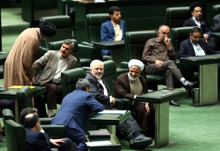 Iranian Foreign Minister Mohammad Javad Zarif (C) smiles as he chats with parliament members during a session in Tehran on October 13, 2015 in which parliament approved its nuclear deal with world powers