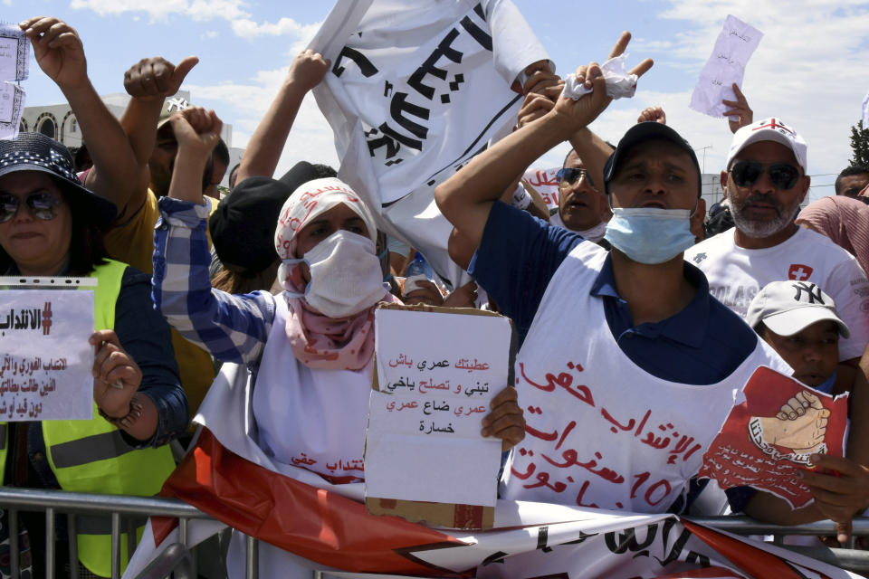 Tunisian Graduates unemployed hold a placards that reads "I spend all my life to build and reform, but you make me lost my life" during a protest in Tunis after Tunisian Prime Minister Elyes Fakhfakh announced that public service recruitments will be stopped and the possibility of reduce wages for public service employees, Wednesday June 17, 2020. About 500 unemployed people demonstrated in Bardo square in front of the House of Representatives, which closed a few days ago, the protesters demanding jobs, freedom and dignity. Some of the protesters tried to bypass the security barrier and there was a stampede with the security agents. (AP Photo/Hassene Dridi)