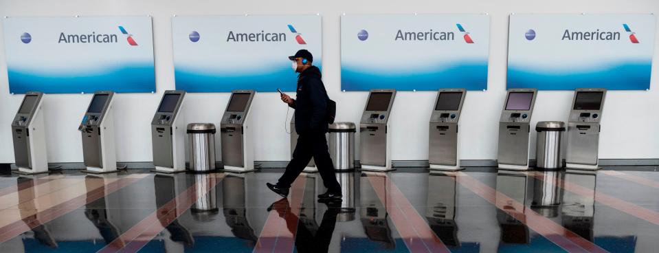 A passenger walks past empty American Airlines check-in terminals at Ronald Reagan Washington National Airport in Arlington, Va., on May 12, 2020.