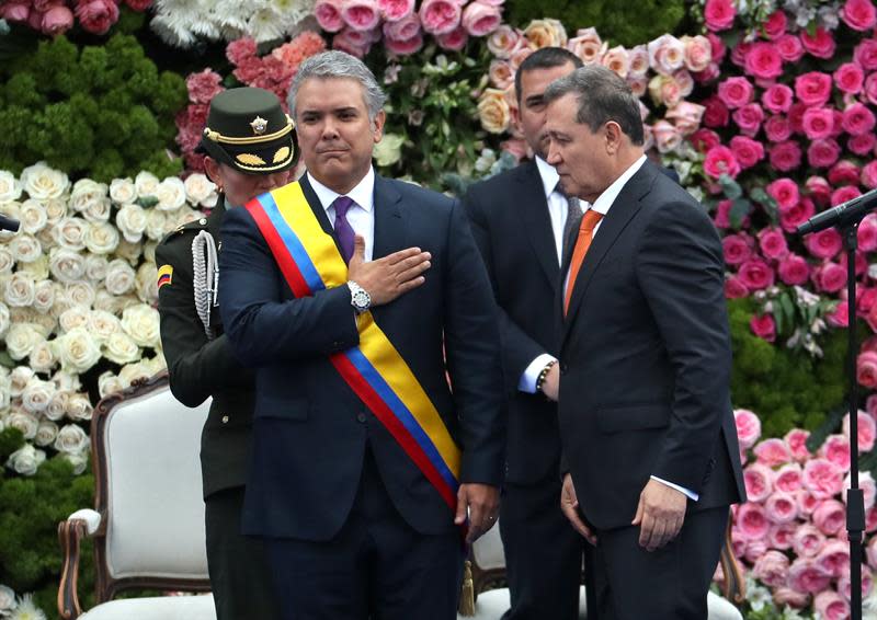 El presidente del Senado, Ernesto Macías (d), le impone la banda presidencial al nuevo presidente colombiano, Iván Duque Márquez (c-i), durante la ceremonia de investidura hoy, martes 7 de agosto de 2018, en la Plaza de Bolívar de Bogotá (Colombia). EFE