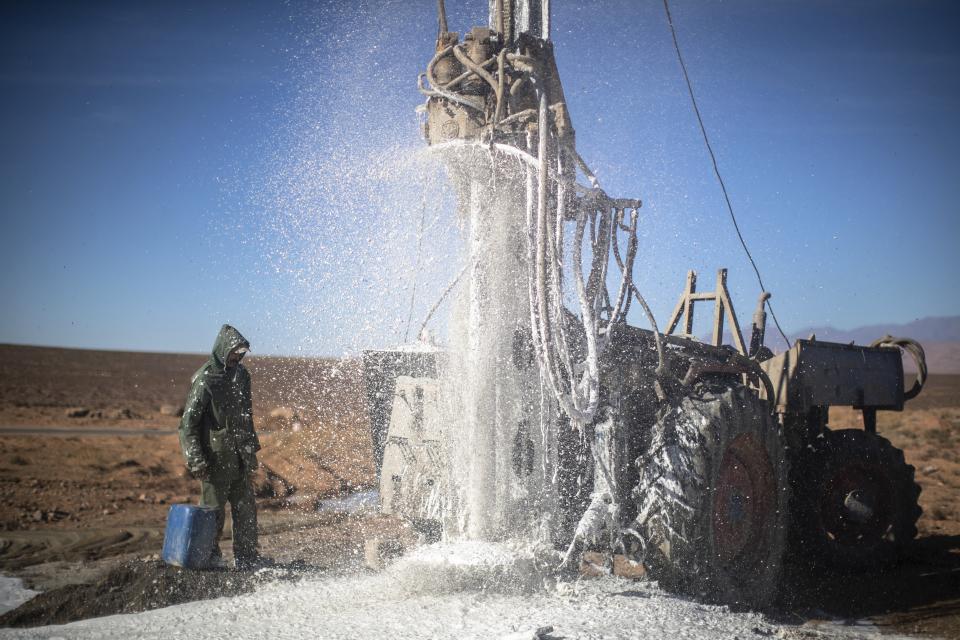 A worker watches as water flows from the ground during a well digging process to provide water for nomads, near Tinghir, Morocco, Monday, Nov. 28, 2022. The centuries-old oases that have been a trademark of Morocco are under threat from climate change, which has created an emergency for the kingdom's agriculture. (AP Photo/Mosa'ab Elshamy)