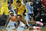 North Carolina forward Armando Bacot falls while chasing the ball with Michigan guard DeVante' Jones (12) during the first half of an NCAA college basketball game in Chapel Hill, N.C., Wednesday, Dec. 1, 2021. (AP Photo/Gerry Broome)