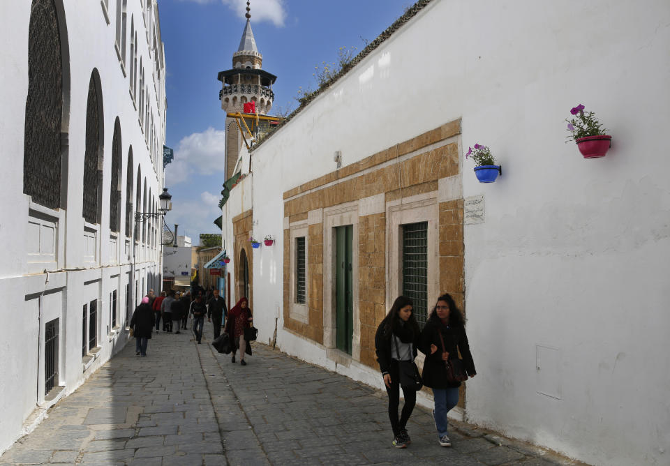 Tunisians walk at an alley in the old city of Tunis, Tunisia, Thursday, March 28, 2019. Tunisia is cleaning up its boulevards and securing its borders for an Arab League summit that this country hopes raises its regional profile and economic prospects. Government ministers from the 22 Arab League states are holding preparatory meetings in Tunis all week for Sunday's summit. (AP Photo/Hussein Malla)